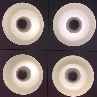 Four circular recessed ceiling lights glow in a square grid against dark panels.