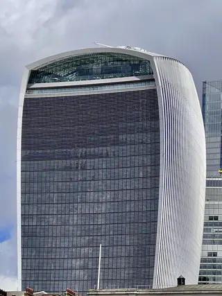 The distinctive curved facade of 20 Fenchurch Street, known as the Walkie Talkie, rises beneath a cloudy sky.