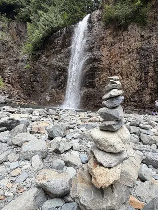 A stack of rocks in front of a waterfall.