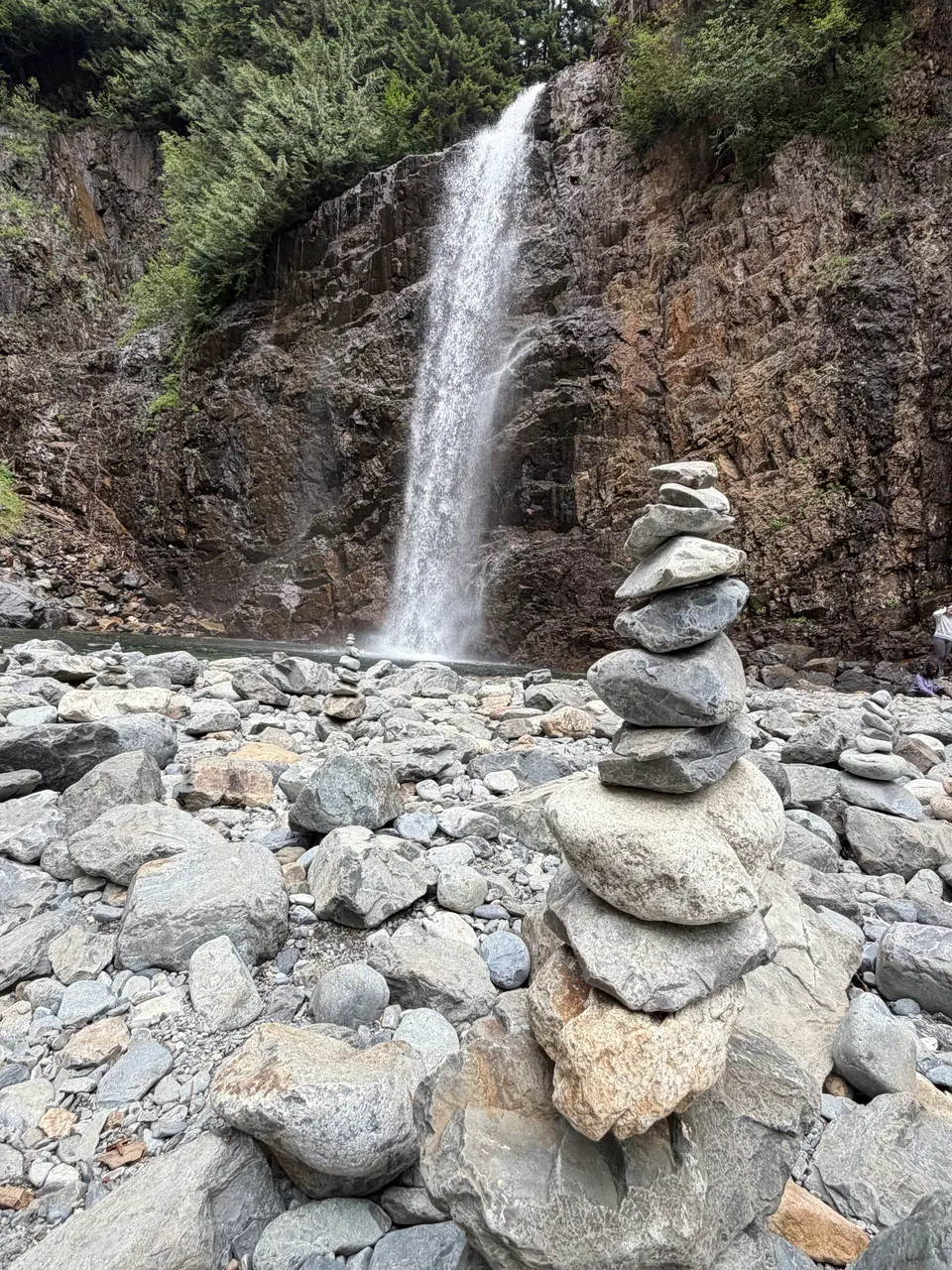 A stack of rocks in front of a waterfall.